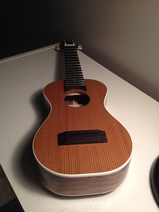 Spruce and walnut ukulele with white bindings and abalone inlayed initials front view